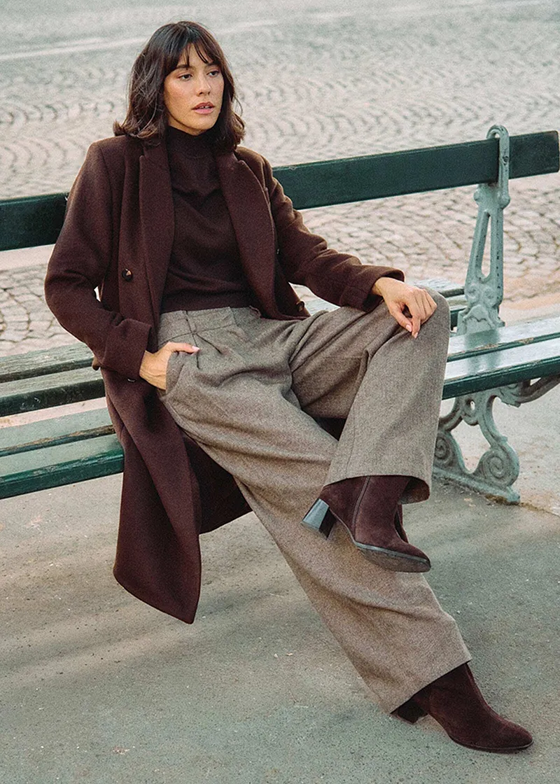 Lange bruine jas, coltrui en wijde tweed broek.