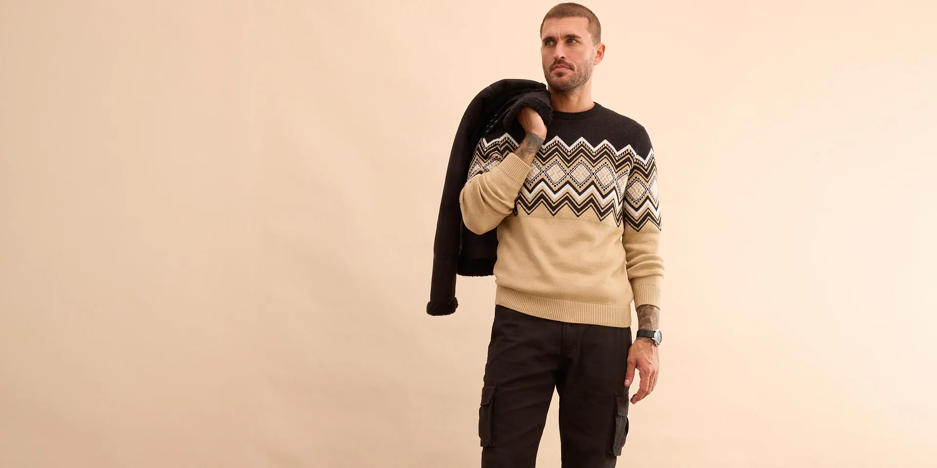 Stijlvolle look: zwarte winterjas, trui met print en jeans voor koude dagen.