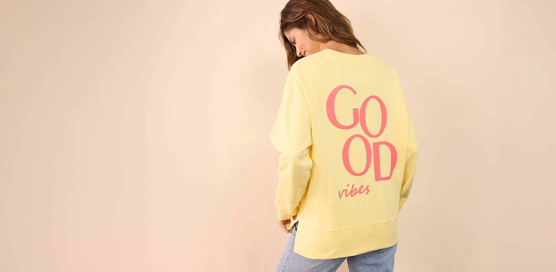 Gele oversized sweater met roze opdruk 'Good Vibes' op de rug.