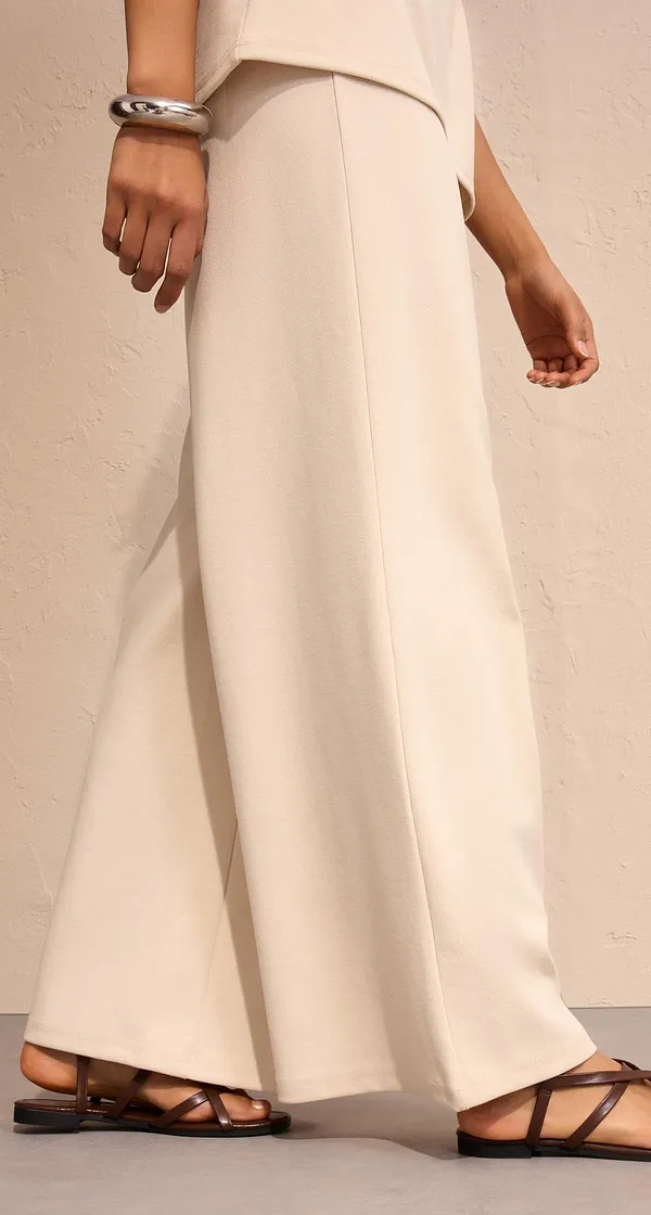 Elegante witte broek gecombineerd met platte sandalen.