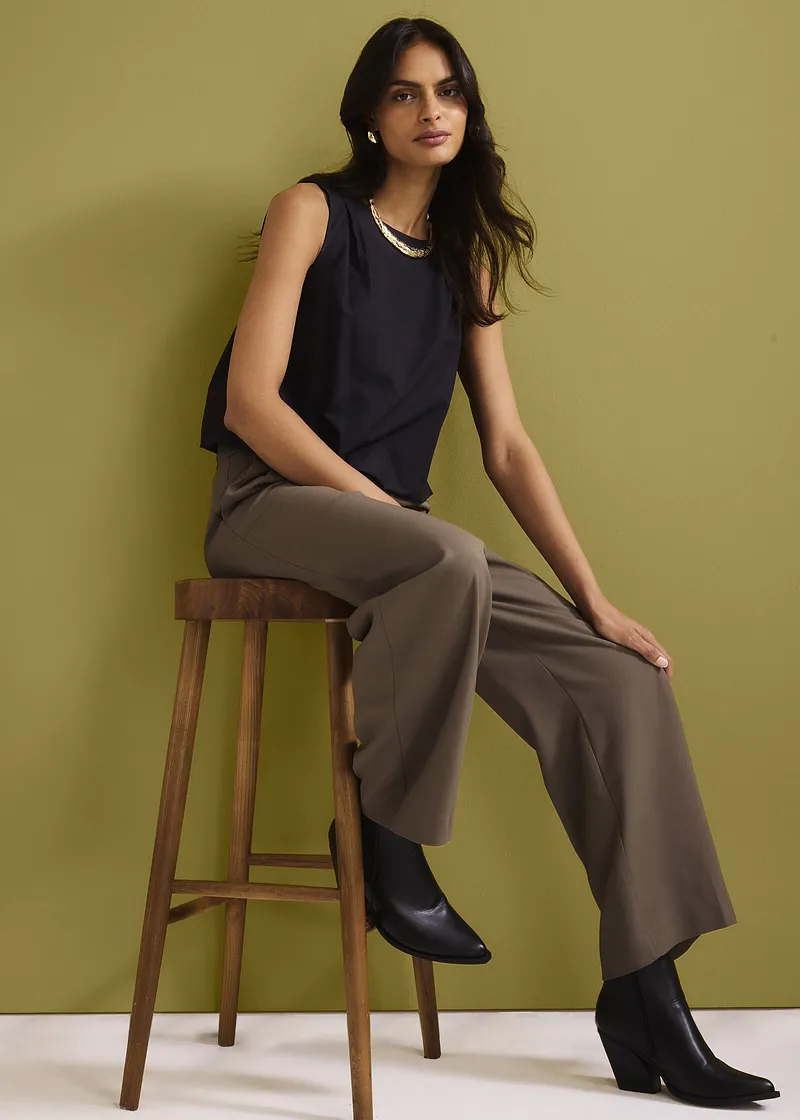 Donkerblauwe top, wijde bruine broek en zwarte laarzen. Elegante, casual look.