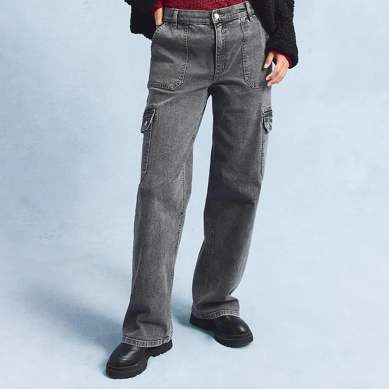 Grijze cargo jeans met ruime zijzakken, gecombineerd met zwarte schoenen.