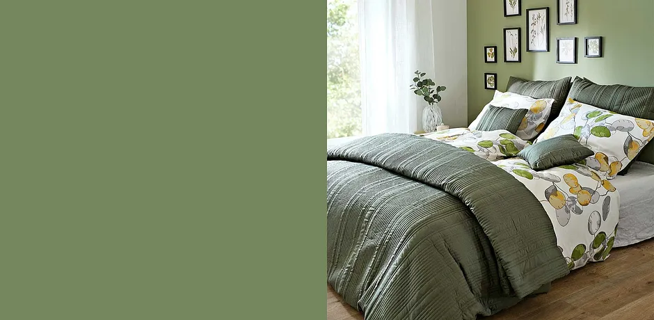 Gezellige slaapkamer met groen beddengoed en kussens. Bloemenpatroon op het beddengoed zorgt voor frisheid.