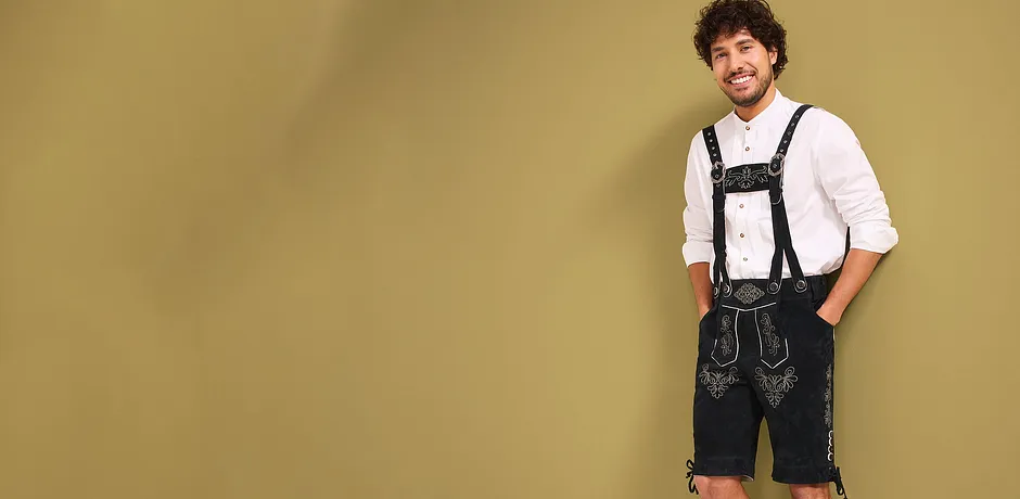 Wit shirt, zwarte lederhose met bretels en decoratieve borduursels.