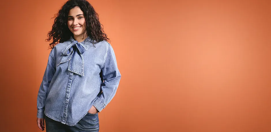 Een lichtblauwe spijkerblouse met een strik geeft de outfit een casual charme.