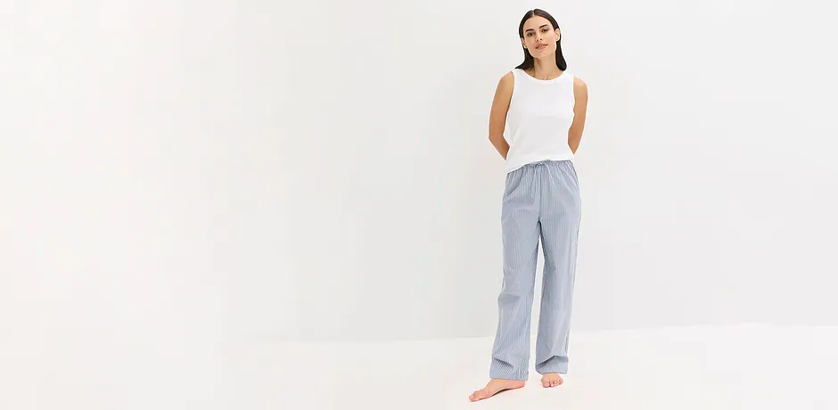 Nonchalante pyjamalook: witte mouwloze top met gestreepte luchtige broek.