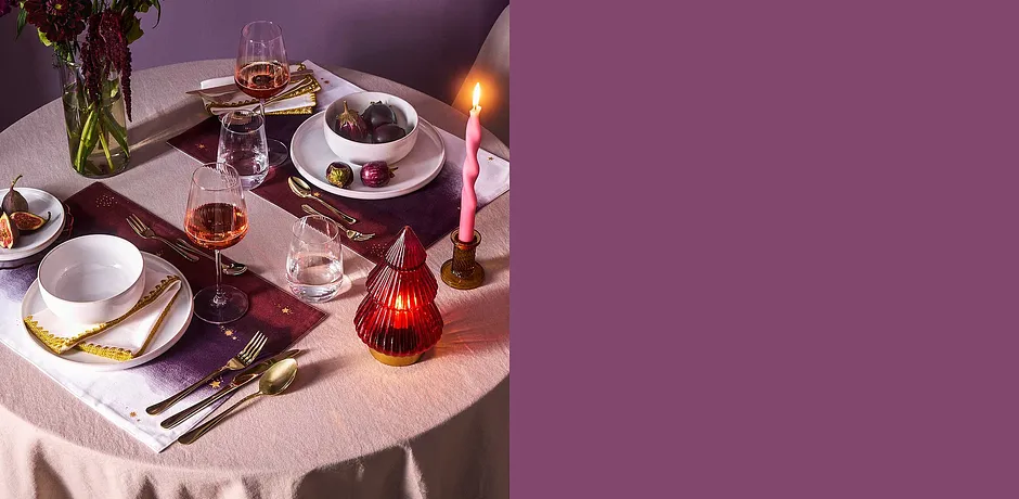 Feestelijk gedekte tafel met tafelkleed, kaarsen en elegante borden.