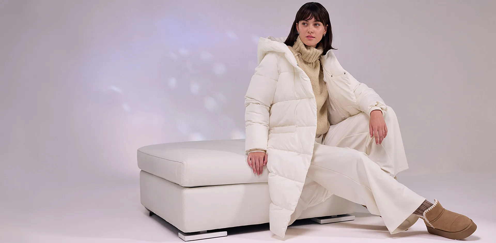 Crèmekleurige gewatteerde jas, witte broek en zacht gevoerde boots.