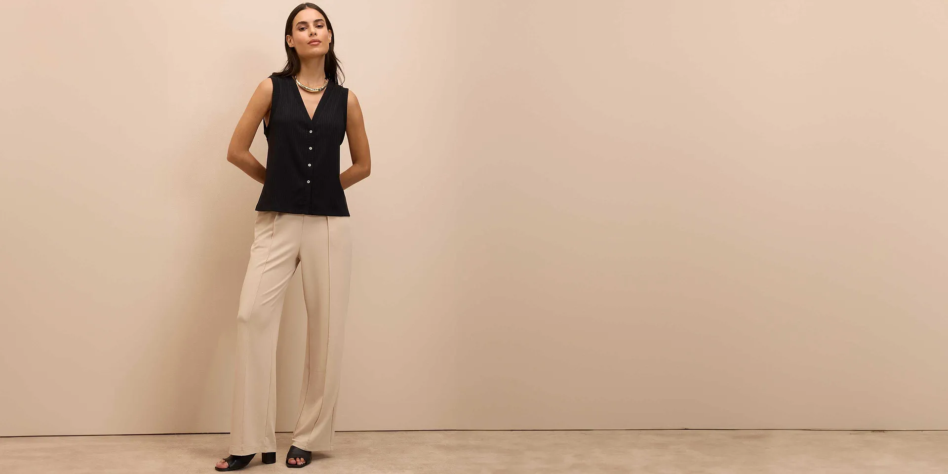 Elegant zwart  gilet met knopen, gecombineerd met beige broek en zwarte schoenen.