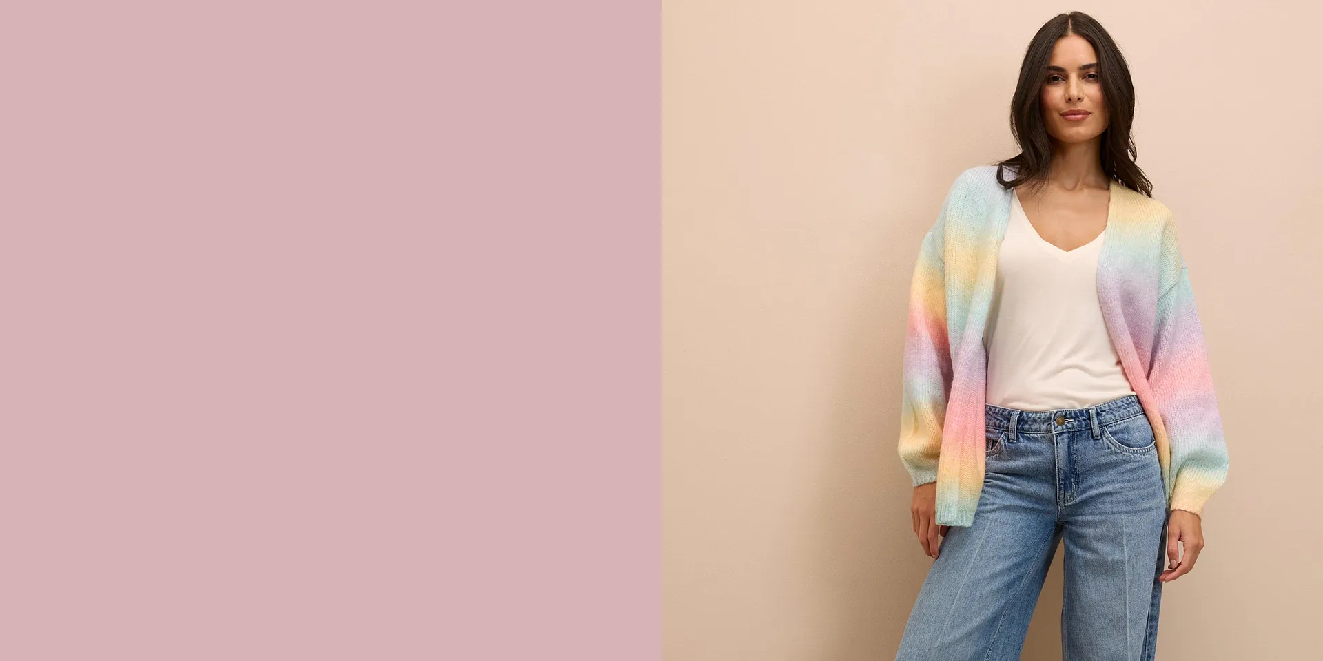 Pastelkleurig gebreid vest over een wit topje, gecombineerd met wijde spijkerbroeken voor een ontspannen look.