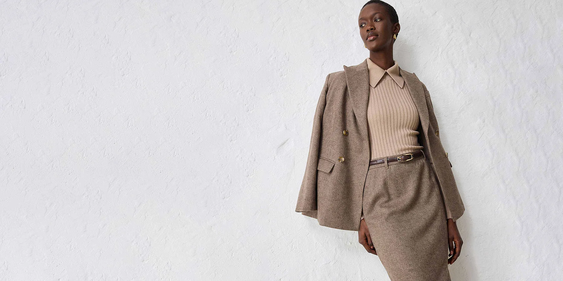 Beigekleurige blazer met een bijpassende trui en rok.