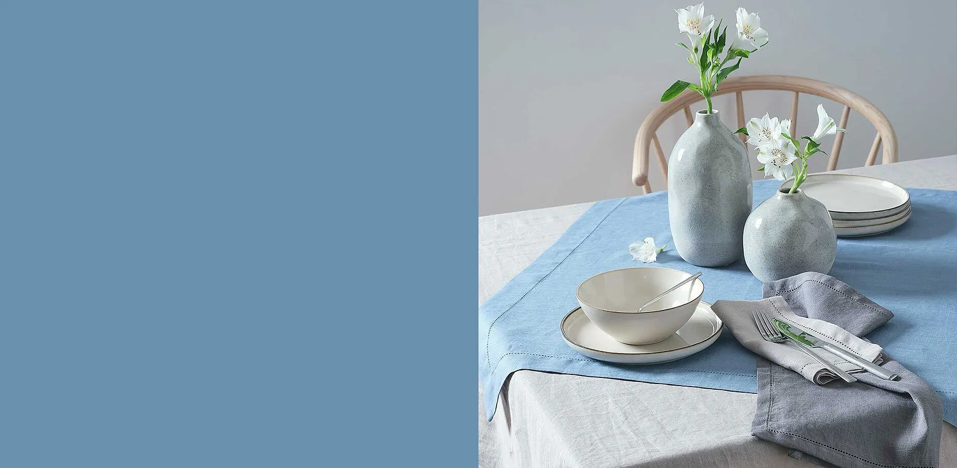 Elegant servies in zachte pastelkleuren op een lichtblauw tafelkleed.