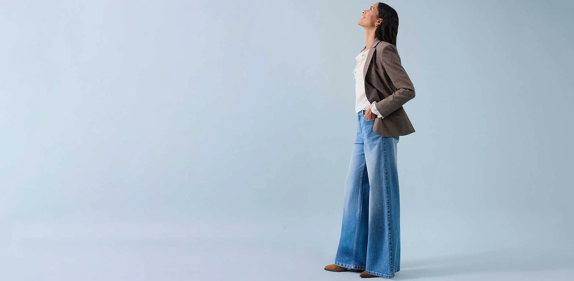 Wijde jeans, licht topje en beige blazer voor een ontspannen stijl.