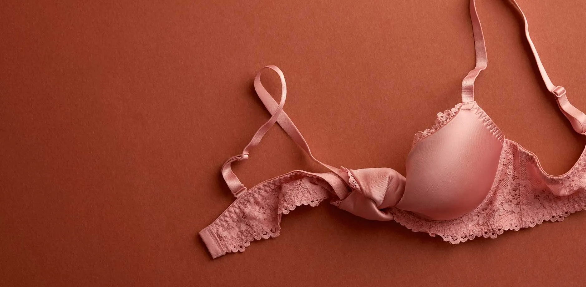 Zachtroze bh met kant op terracottakleurige achtergrond. Elegante lingerie voor vrouwen.
