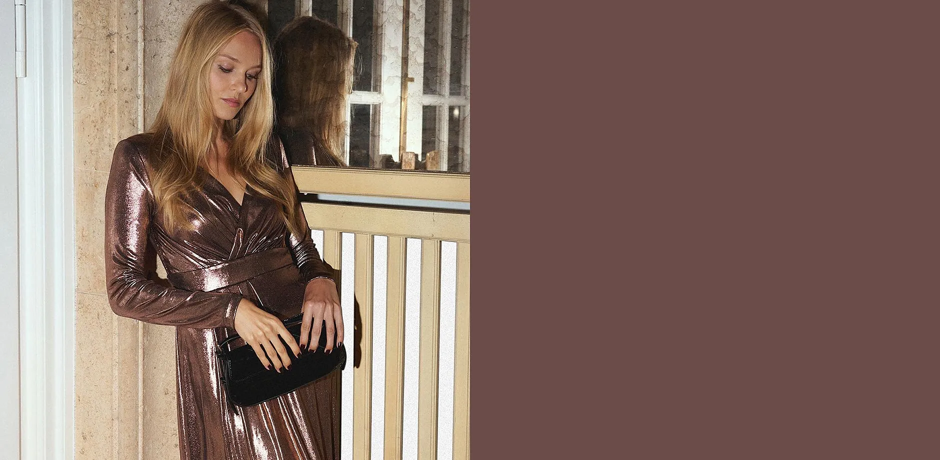 Glanzende jurk met V-hals gecombineerd met zwarte tas.