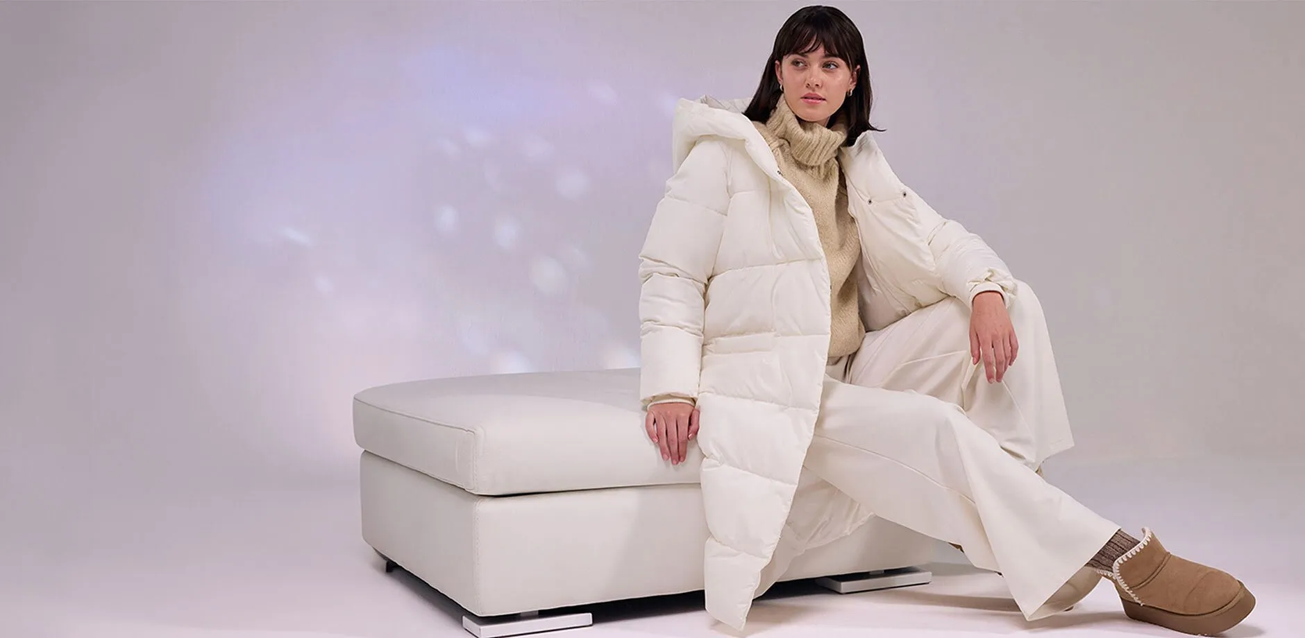 Lange cr&egrave;mekleurige gewatteerde jas, witte broek en zacht gevoerde boots.