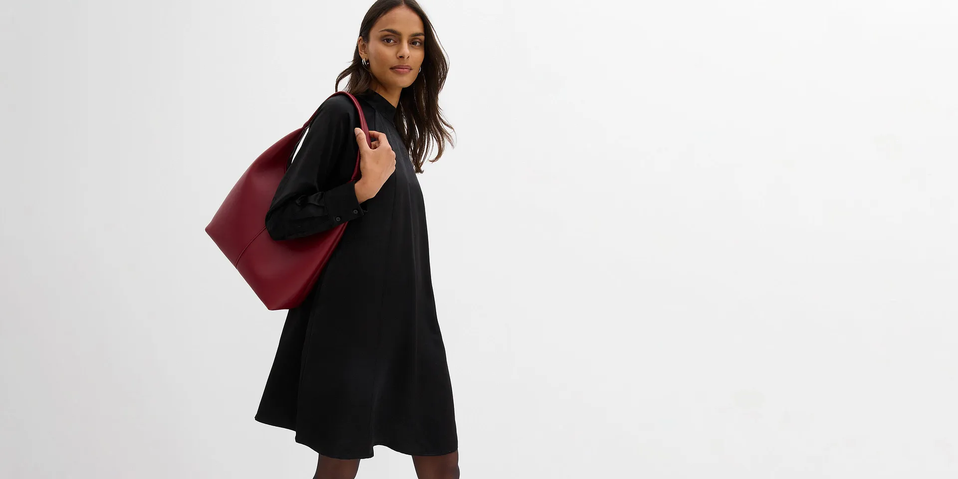 Korte zwarte jurk met hoge, versierde kraag en lange mouwen.  