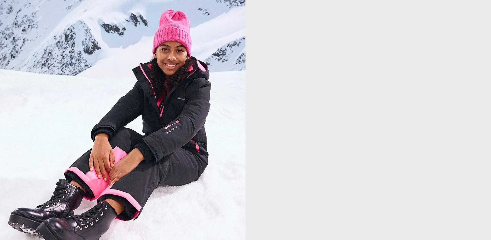 Zwarte winterjas en broek, roze muts.