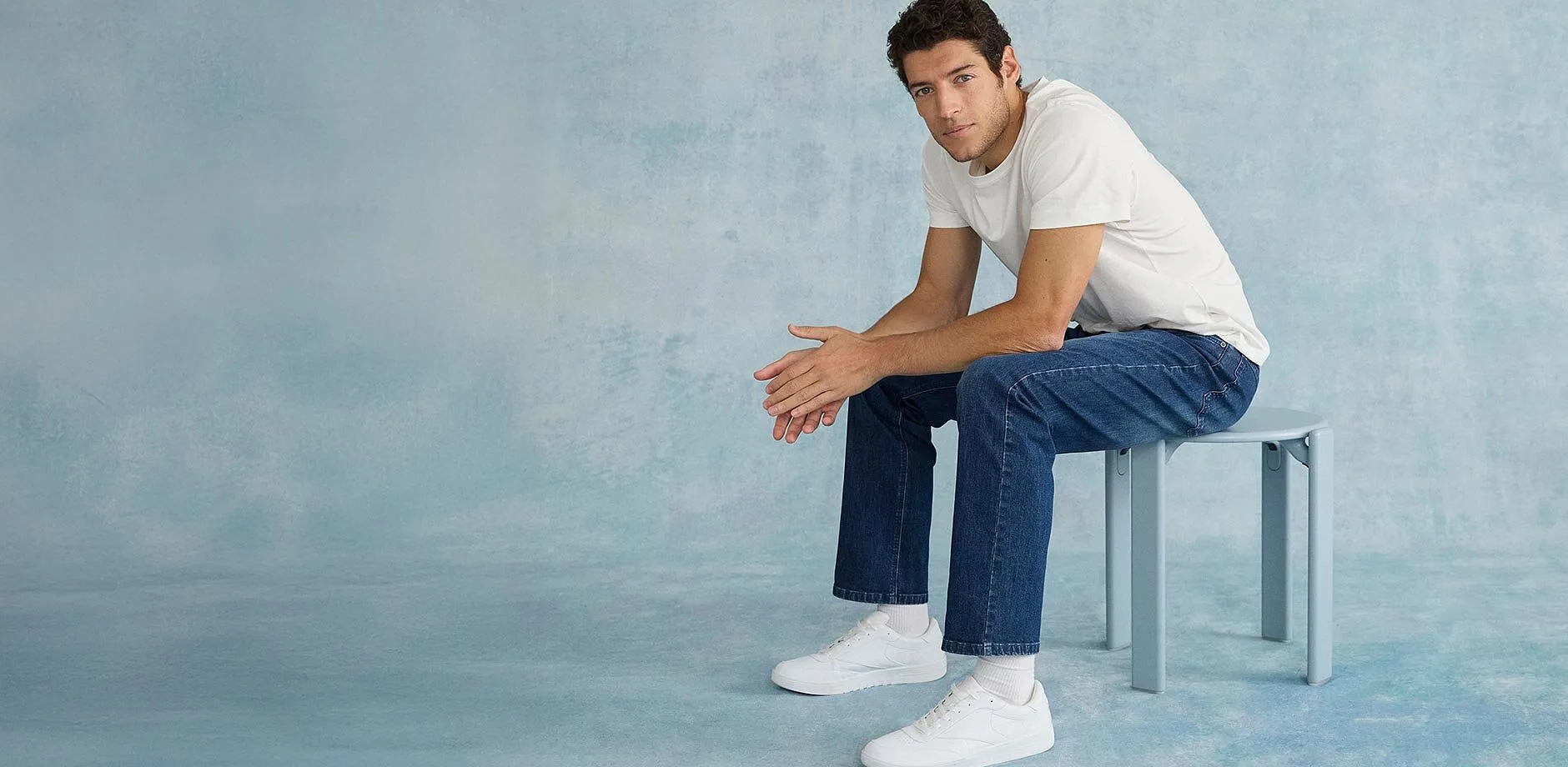 Minimalistisch wit T-shirt, klassieke blauwe jeans en witte sneakers.