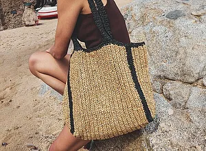 Zomerse strandtas van stro met zwarte accenten.