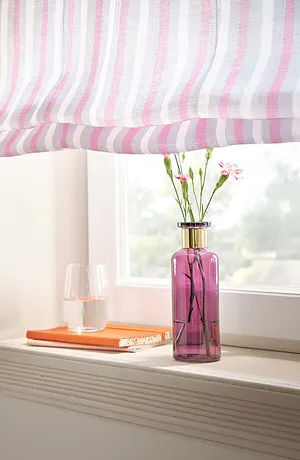 Gestreepte gordijnen in pastelkleuren siert het raam, met daaronder een roze vaas met bloemen.