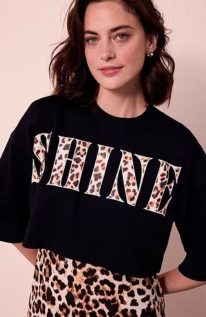 Frau mit SHINE-Leo-Shirt und Leo-Rock vor heller Wand