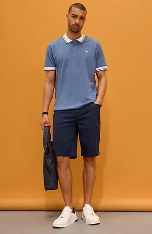 Lichtblauw poloshirt met een witte kraag en een donkere broek. Sportief en toch elegant.