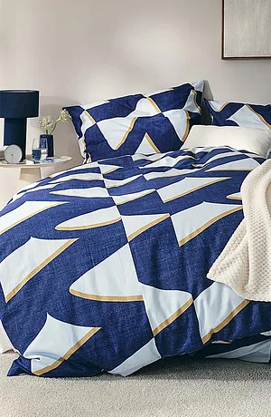 Geometrisch beddengoed in blauw en wit, aangevuld met een crèmekleurige deken.