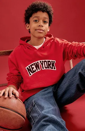 Rode hoodie met New York schriftopdruk en blauwe jeans.