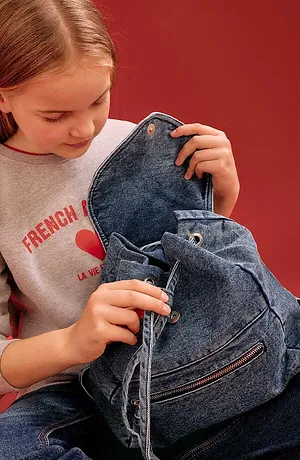 Grijs sweatshirt met rode opdruk en een blauwe denimrugzak. Casual dagelijkse look voor jonge mensen.