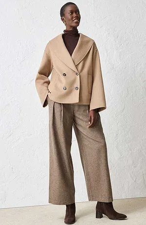 Beige jas met wol, bruine coltrui en een wijde broek.