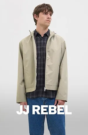 Geruit overhemd onder een beige jas, gecombineerd met een blauwe jeans.