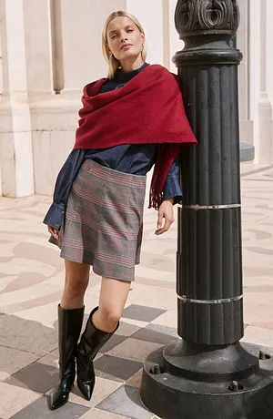 Rode sjaal, donkerblauwe blouse, geruite rok en zwarte laarzen.