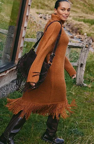 Braunes Kleid mit Fransen kombiniert mit schwarzen Stiefel und Tasche.