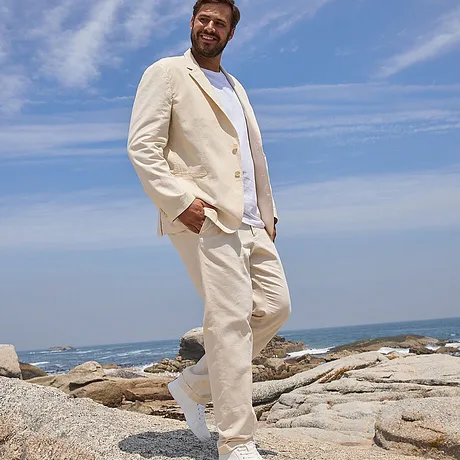Elegante zomerset in crèmekleur: luchtige blazer, witte broek en T-shirt, met bijpassende lichte schoenen.
