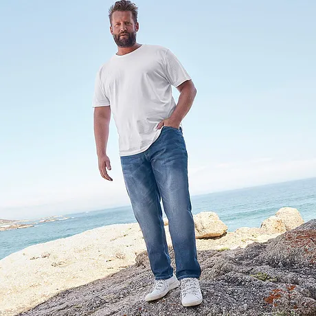 Casual strandlook: Wit T-shirt en relaxte jeans, aangevuld met comfortabele witte sneakers.