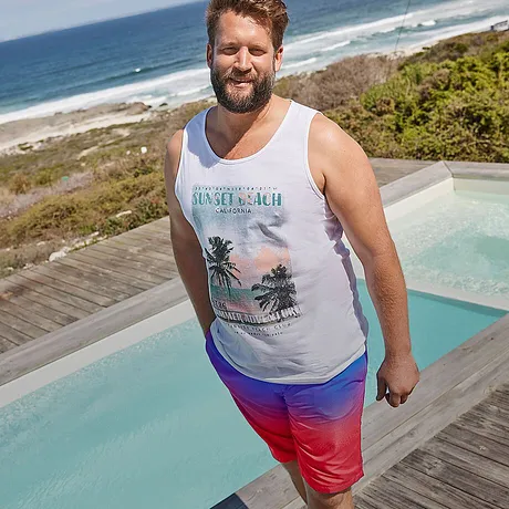 Witte tanktop met tropisch motief, kleurrijke zwemshorts in rood en blauw.