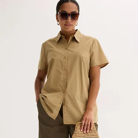 Elegante beige kortarmblouse met kraag, gecombineerd met een bruine rok en een stijlvolle zonnebril.