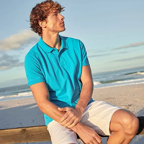 Zomerse strandlook: Turquoise poloshirt en lichte shorts voor een ontspannen vakantiesfeer aan zee.