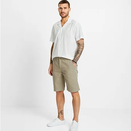 Wit kortarm overhemd met patroon, beige shorts en witte sneakers.