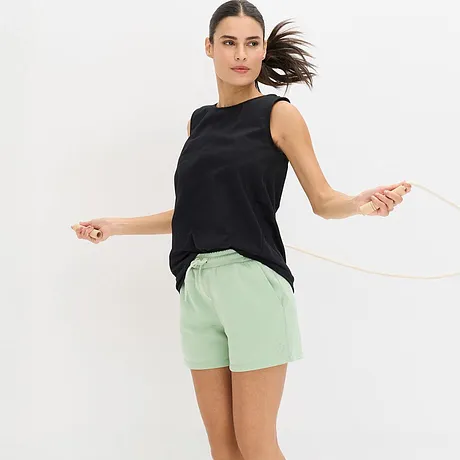 Schwarzes Top kombiniert mit mintgrüner Funktions-Sportshorts.