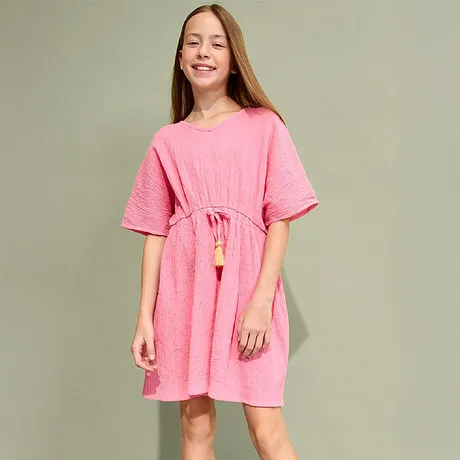 Zomerse roze jurk met korte mouwen, taillekoord en kwasten. Daarbij gouden sandalen.