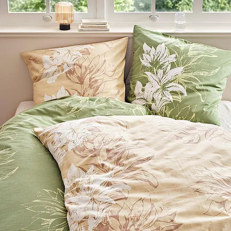 Bloemenbeddengoed in pasteltinten: groen en beige met delicate bloemmotieven versieren het bed.