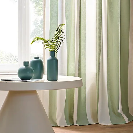 Licht gordijn in pastelgroen en wit siert het raam en geeft de kamer elegantie.