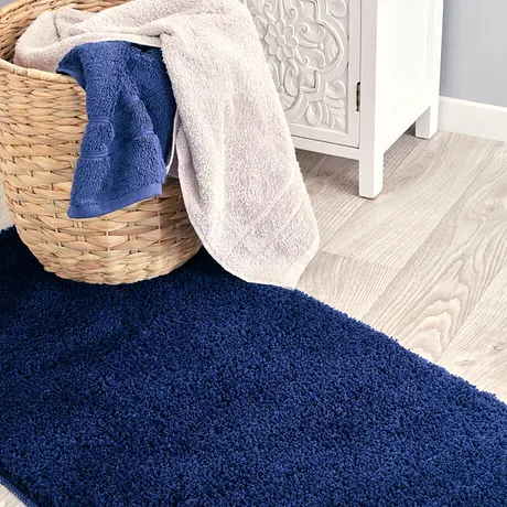Zachte handdoeken in blauw en beige liggen in de mand op een fluffy tapijt.