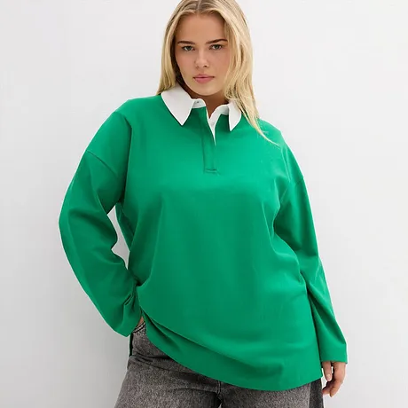 Smaragdgroen poloshirt met witte kraag, gecombineerd met een grijze broek.