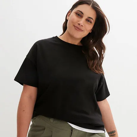 Een eenvoudig zwart T-shirt met ronde hals en korte mouwen, gecombineerd met een olijfgroene broek.