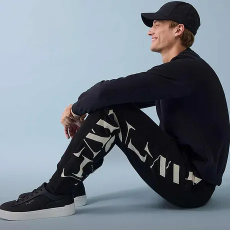 Donkere joggingbroek, trui en sneakers maken de sportieve look compleet.