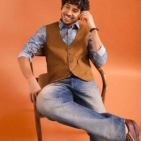 Bruin gilet over een blauw overhemd met patroon, gecombineerd met spijkerbroek.