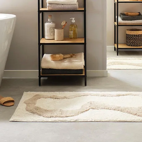 Zachte handdoeken en een pluizig badmatje zorgen voor comfort in de stijlvol ingerichte badkamer.